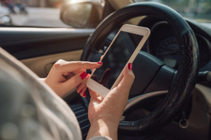 Uber Accident Lawyer Monmouth County, NJ - Mockup image of woman hand using mobile smartphone with blank screen while driving car and leaving home. clipping path.